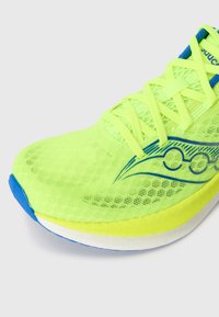Baskets de sport jaune fluo avec un dessus en maille respirante, des accents bleus et une semelle blanche rembourrée. Elles sont dotées d'un système de laçage.