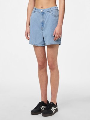 Shorts en denim à lavande claire avec une coupe décontractée, dotés d'une fermeture à bouton et de poches avant, associés à des baskets noires avec des accents blancs.