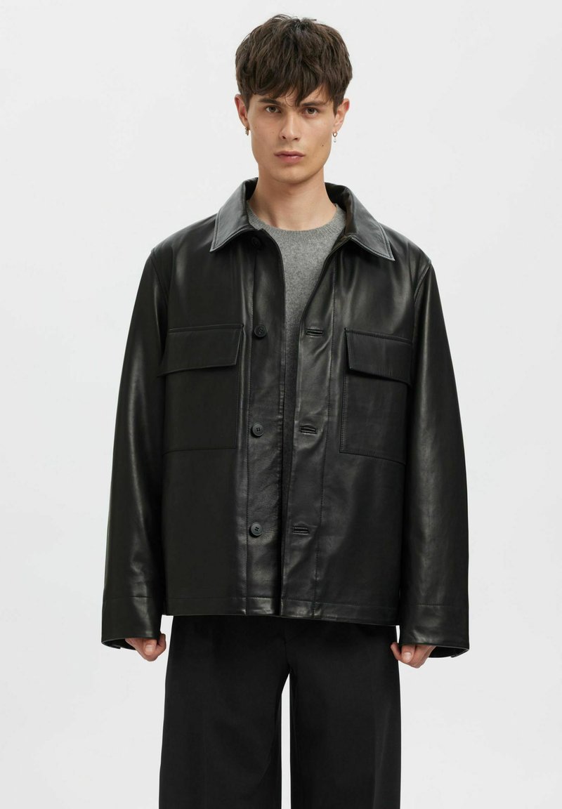 Must nahkjakk kraeulikujundusega, kinnitatav nööpidega, kahe rinnanurgaga ja lõdva lõikega. Sile tekstuur, lihtsad õmblused.