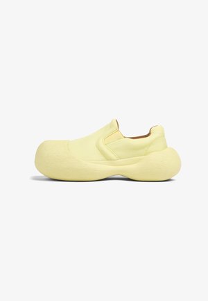 Scarpa slip-on giallo chiaro con superiore testurizzato, punta arrotondata e suola spessa e ammortizzata. Cuciture minimali e senza hardware visibili.