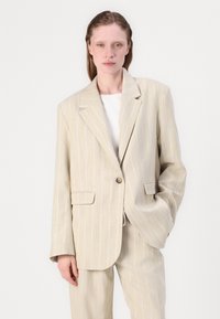 Beige pinstripe blazer met een enkele knop, gelapte revers en twee voorzakken. Draag het over een wit topje, met een ontspannen pasvorm.