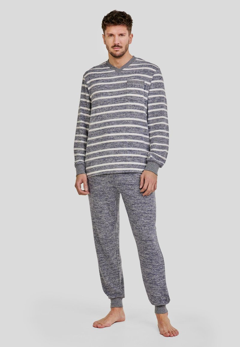 Conjunto de loungewear a rayas grises y blancas. La parte superior tiene un escote en V y mangas largas; los pantalones presentan puños ajustados. Textura suave, ajuste casual.
