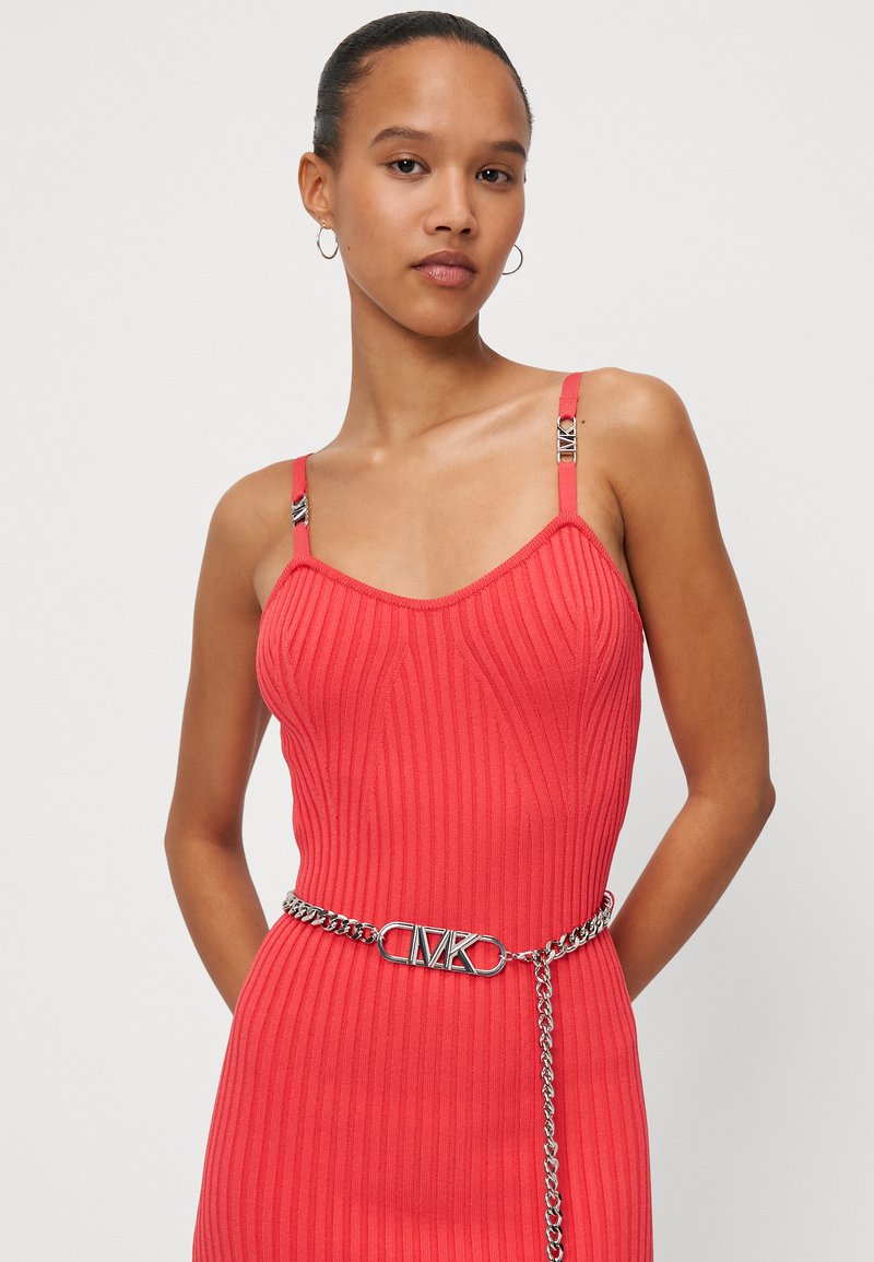 Rotes geripptes Kleid mit dünnen Trägern, ausgestattet mit silbernen Hardware-Details an den Trägern und einem silbernen Kettengürtel mit einem Logo-Verschluss.