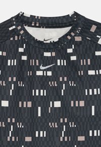 Camiseta deportiva de Nike en negro y gris con diseños en forma de cuadrados y rectángulos pixelados en blanco y rosa pálido.