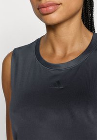 Μαύρο αθλητικό φανελάκι με ριμπ υφή, με στρογγυλή λαιμόκοψη και διακριτικό μαύρο λογότυπο Adidas στο μπροστινό μέρος.