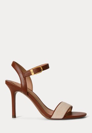 Smeđa kožna sandala na visoku petu s bež pletenim remenom preko prstiju i podesivim remenom za gležanj sa zlatnom kopčom, tanka šiljasta potpetica.