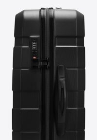 Tvrdý černý kufr s texturovaným povrchem, vybavený kombinovaným zámkem a bočním madlem. Design zahrnuje vzor obdélníkové mřížky.