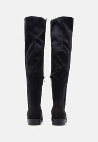 Black over-the-knee boots with a smooth exterior, suede accents, zip details on the sides, and a rounded toe design. Rubber heel.