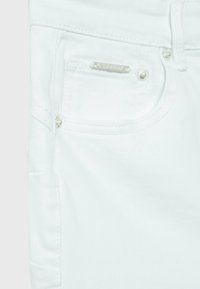 Jean en denim blanc avec un détail de quincaillerie argentée sur la poche et des coutures soignées. Texture lisse et coupe slim.