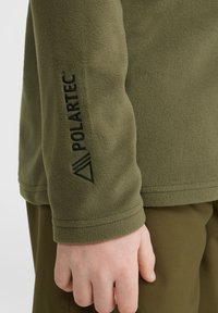 Veste en polaire vert olive avec logo et design en triangle sur la manche, dotée d'une texture lisse et d'un ourlet cousu.