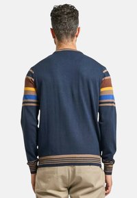 Cardigan in maglia blu navy con accenti a righe marroni, gialli e blu sulle maniche, polsini e orlo a coste. Texture liscia.