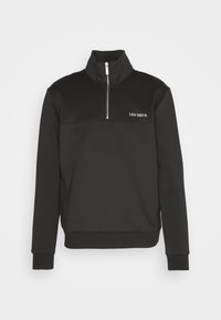 Sudadera negra de media cremallera hecha de tejido texturizado, con un cuello alzado, puños acanalados y el nombre de la marca "LES DEUX" en bordado blanco.