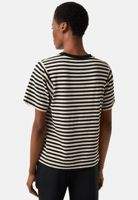 Koszulka z krótkim rękawem w poziome czarno-kremowe paski, z okrągłym dekoltem, wykonana z miękkiej bawełny.