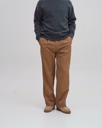 Pantalons beiges à coupe décontractée, en tissu lisse. Assortis à un pull gris foncé et des mocassins de couleur claire.