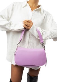 Borsa a tracolla in pelle viola con una forma curvata e strutturata. Tracolla regolabile e accessori in argento. Texture liscia con una leggera grana.