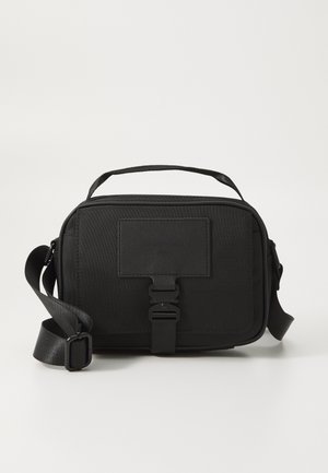 Schwarz rechteckige Tasche aus strukturiertem Stoff, mit einem oberen Griff, verstellbarem Schultergurt, vorderem Schnallenverschluss und einem minimalistischen Design.