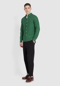 Groen overhemd met kraag, lange mouwen en een slimfit. Gecombineerd met zwarte broek en bruine veterschoenen.