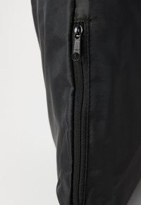 Saco de tecido preto com um fecho de correr de um lado, apresentando uma textura suave e mate, com costuras robustas ao longo das bordas.