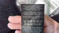 Black fabric care label showing 92% polyester and 8% nylon composition, with washing instructions and care symbols printed in multiple languages.