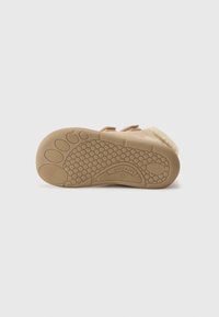 Semelle en daim beige avec un motif en nid d'abeille texturé, des formes arrondies et un design flexible pour une meilleure adhérence et un confort accru.