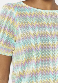 Top a maniche corte in un leggero tessuto a maglia, caratterizzato da un motivo a zigzag nei delicati colori pastello di blu, lavanda, giallo e bianco. Collo rotondo.