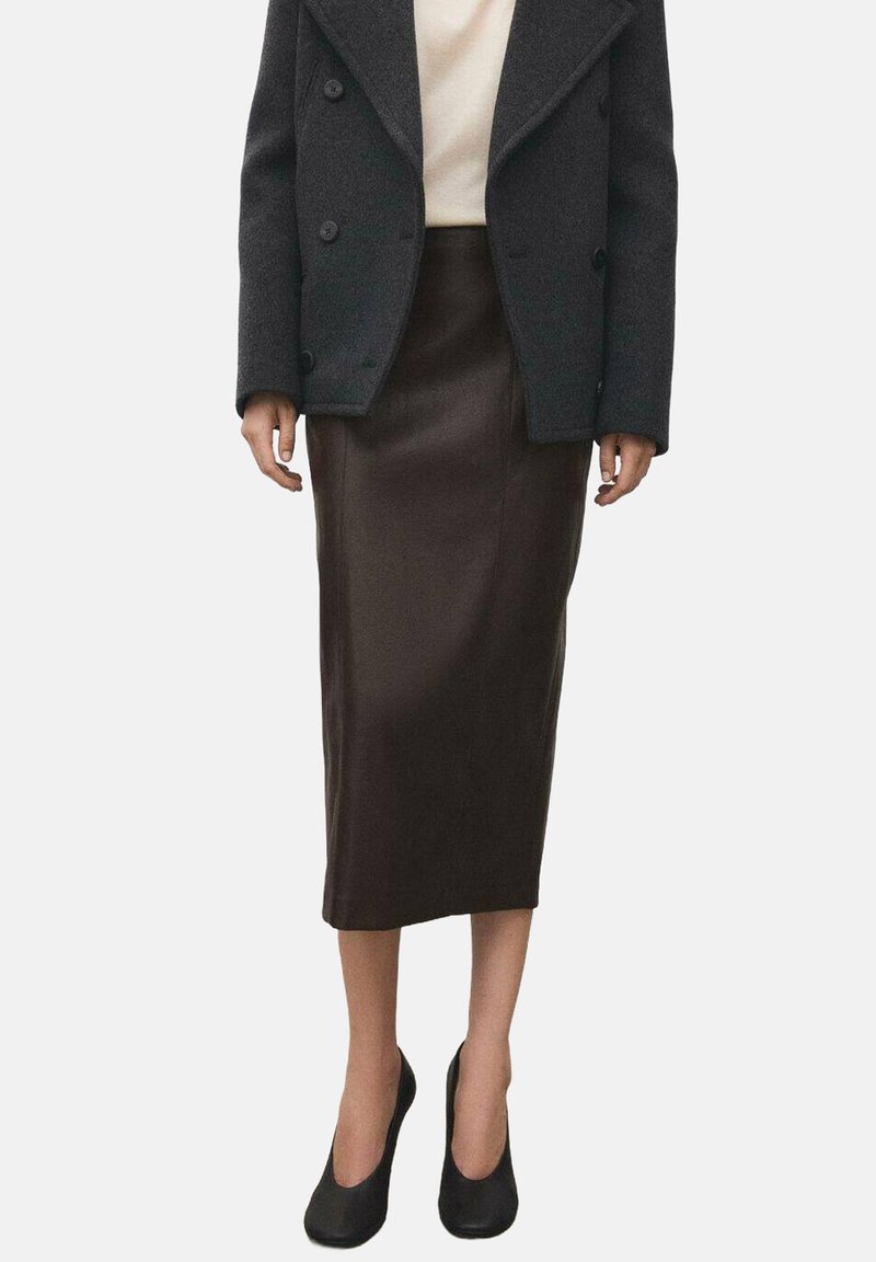 Falda de cuero marrón, hasta la rodilla, con una textura suave. Combinada con un abrigo gris de doble botonadura y tacones negros.