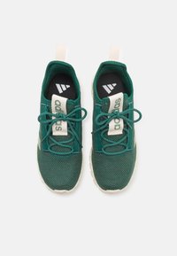 Gröna mesh idrottsskor med vita snören och detaljer. Har en texturerad yta, vadderade innersulor och en ljusfärgad sula.