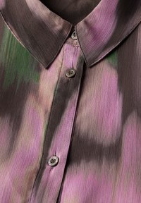 Blusa con colletto e motivo gradient in rosa, verde e marrone. Presenta bottoni e un tessuto testurizzato e setoso.