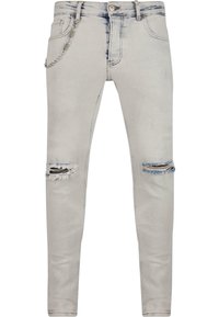 Világosszürke, slim fit farmernadrág, melynek térdhajlataiban koptatott kivágások találhatók, és az elülső zsebbe ezüstlánc tartozik.