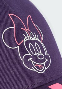 Gorra morada de tela con un contorno blanco de la cara de un personaje de dibujos animados con un lazo rosa, superficie texturizada y acentos cosidos.