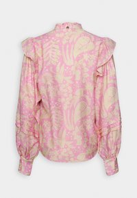 Blouse florale rose avec épaules volantées, manches longues, fermeture à boutons au niveau du col, et tissu doux et texturé. Présente un motif décoratif.