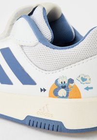 Białe sneakersy z niebieskimi akcentami, z siateczkowej cholewki z teksturą, z grafiką w stylu kreskówkowym oraz logo Adidas na podeszwie. Zapięcie na rzep.