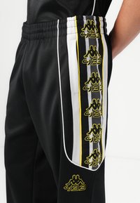 Kappa BANDA ARESTE KAPPA X 433 UNISEX - Tracksuit bottoms - black/white/yellow