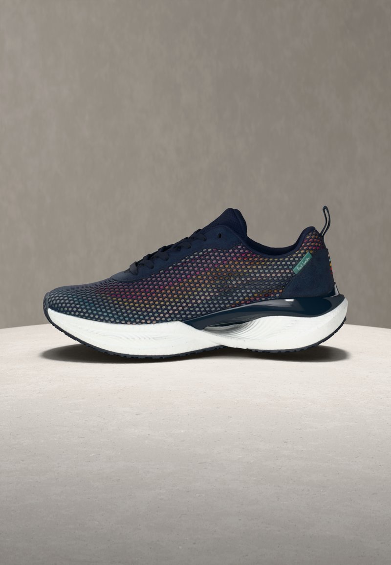 Μαύρο αθλητικό παπούτσι με μεγάλη λευκή μαλακή σόλα και πολύχρωμο επάνω μέρος από πλέγμα, εμφανίζεται σε προφίλ σε ουδέτερη επιφάνεια και φόντο.