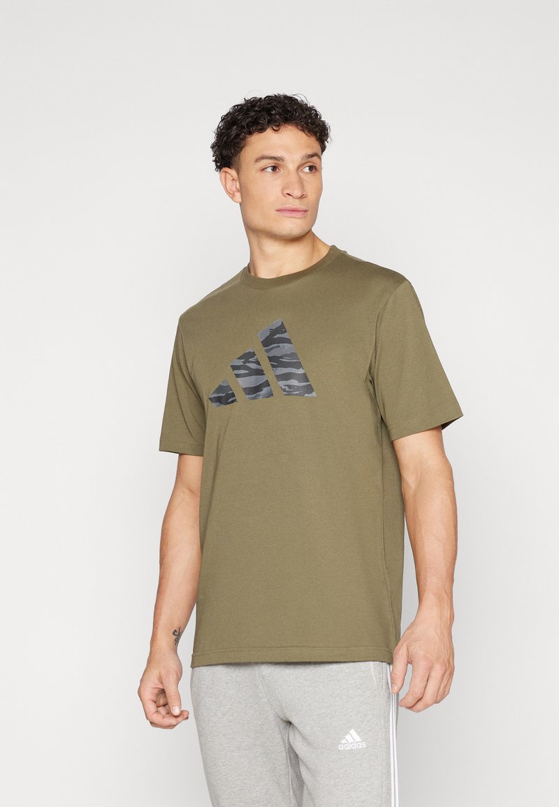 Maslinasto zeleni pamučni majicu s crnim camo uzorkom u tri pruge sprijeda. Klasičan okrugli izrez i kratki rukavi.
