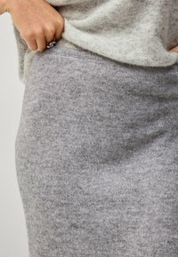 Grijze wollen rok met een gladde textuur, aansluitend ontwerp en elastische taille, gecombineerd met een lichtgrijze gemêleerde top.