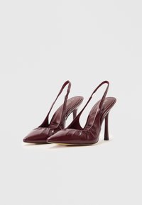Mørk røde spisse slingback høyhælte sko med slanke stiletthæler og lett samlede lærdetaljer foran.