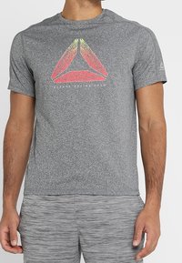 Šedé tričko s krátkým rukávem vyrobené z lehkého materiálu, které v centru zdobí jasně barevná trojúhelníková grafika a text značky.