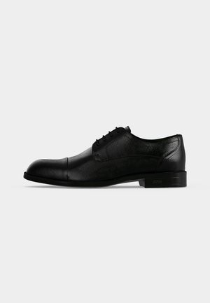 Schwarzer Leder-Herrenschuh im formellen Oxford-Stil mit geschlossener Schnürung, Kappenspitze und niedrigem gestapeltem Absatz, von der Außenseite gezeigt.