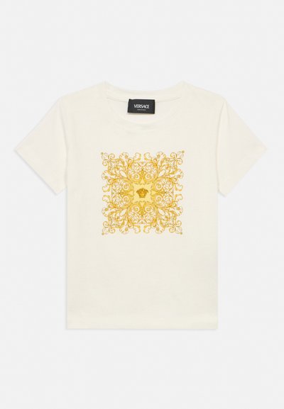 Bela kratka majica s kratkimi rokavi znamke Versace z osrednjim zapletenim zlatim baročnim vzorcem, ki vključuje logotip glave Meduze.