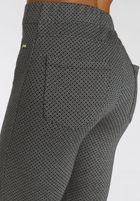 Zwarte leggings met een diamanten patroon, met een fitted pasvorm, textielstructuur en accentstiksels bij de tailleband.