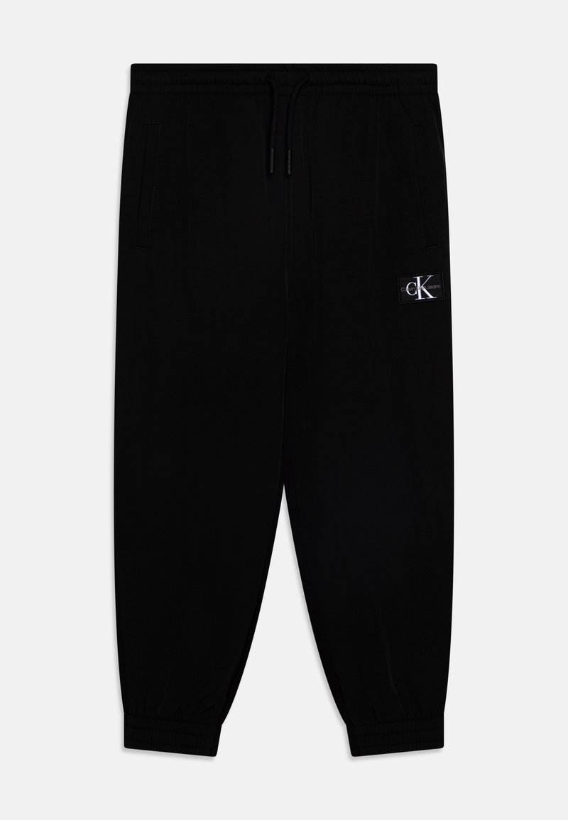 Black jogger pants made of soft fabric, featuring an elastic waistband with drawstring, side pockets, and a small logo patch.