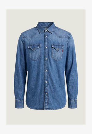 Blå denimskjorte med lange ærmer, trykknapper, to brystlommer med klap og en spids krave, vist på en ensartet lys baggrund.