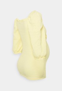 Top amarelo texturizado com mangas bufantes, textura canelada e formato justo. Acentos de babado elástico nas mangas e na bainha inferior.