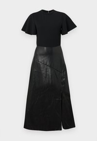 Robe noire avec des manches courtes flottantes, un corsage ajusté et une longue jupe en simili cuir avec une couture asymétrique et une fente à l'avant.