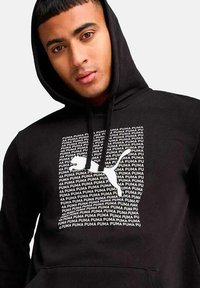 Sudadera negra con capucha que presenta un patrón de texto repetitivo con la palabra "PUMA" y un logotipo blanco de PUMA. Tejido suave y corte estándar con capucha ajustable.