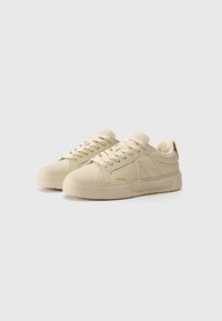 Beige synthetische sneakers met vlakke crèmekleurige veters, rubberen zolen en gouden branding. Beschikt over een soepele textuur en driehoekige accenten aan de zijkant.