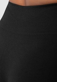 Leggings noires taille haute avec une texture côtelée et une finition lisse, au design ajusté et sans motifs visibles.
