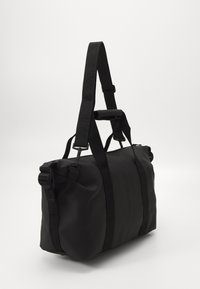 Schwarze Duffel-Tasche aus strapazierfähigem Material, mit glatter Oberfläche, verstellbaren Trägern und einem oberen Handgriff für vielseitige Trageoptionen.