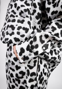 Leopardenmusterhemd in Schwarz und Weiß, aus glattem Stoff gefertigt. Mit geknöpften Manschetten und einer Brusttasche für zusätzliche Details.